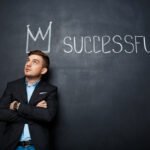 picture of suited, happy man over blackboard with crown above his head and text successful.